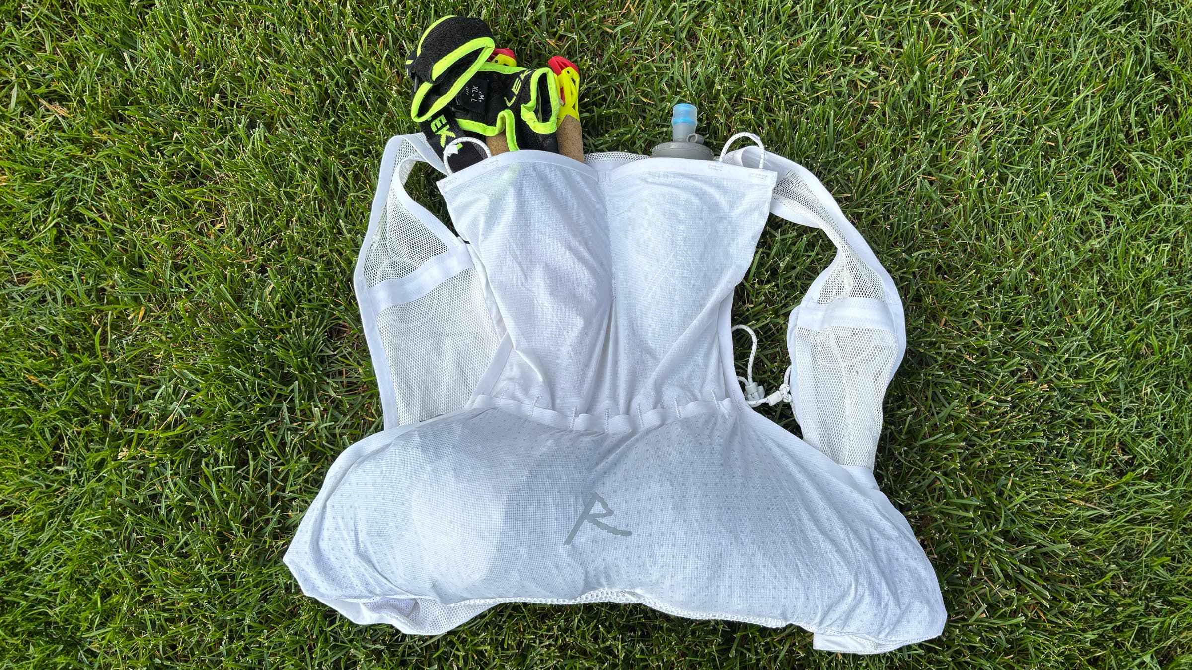View of back of Raide LF 5L running vest with poles and water bottle in pockets.
